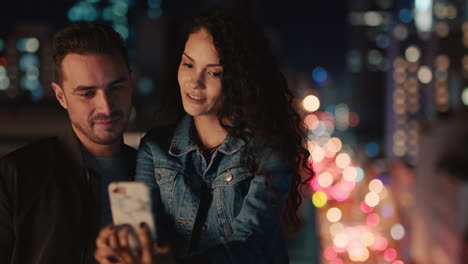 happy caucasian couple posing for photo on rooftop young woman using smartphone photographing romantic date sharing evening in city at night