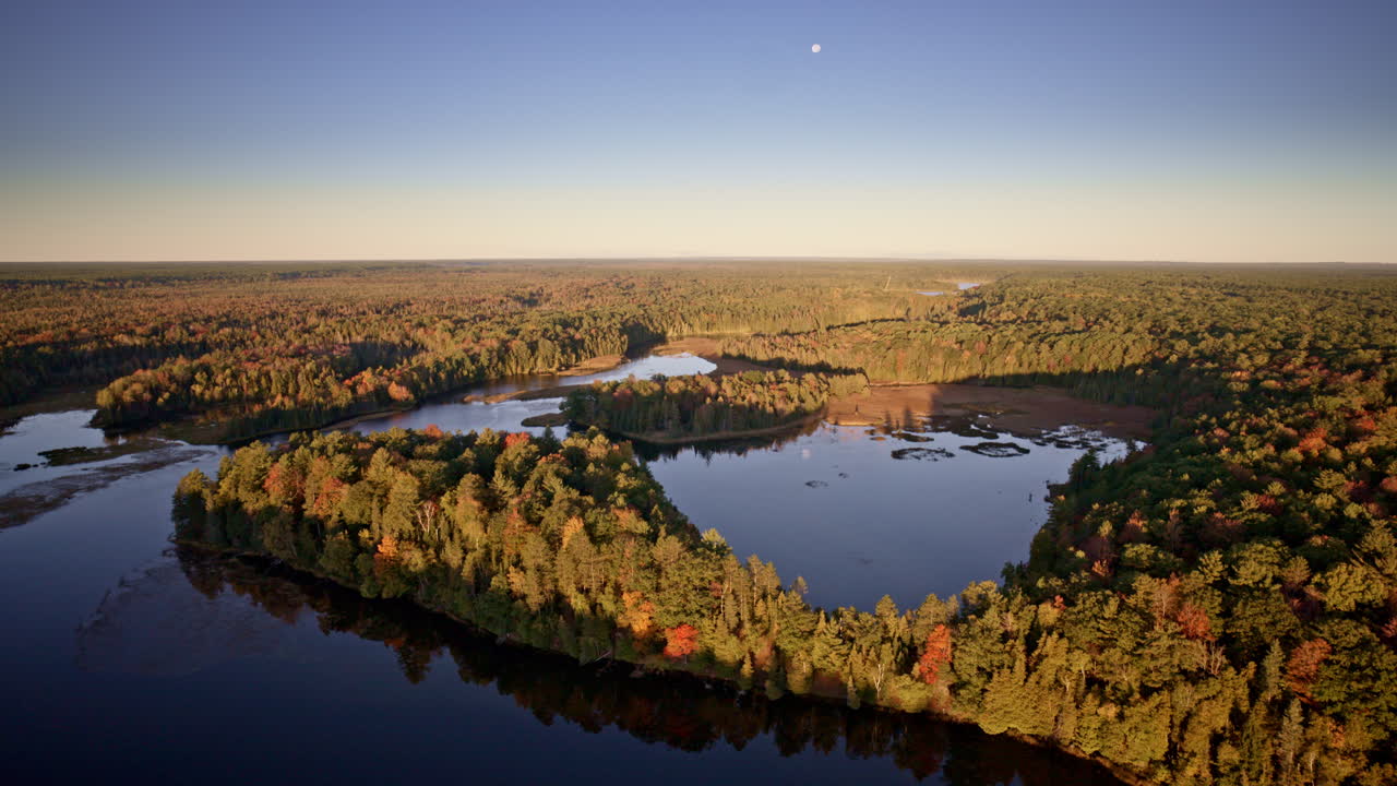 High-altitude shot of a river immersed in fall forest colors