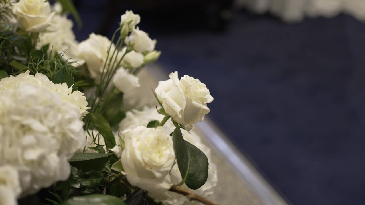 Primo piano di rose bianche e verde in un'elegante composizione floreale