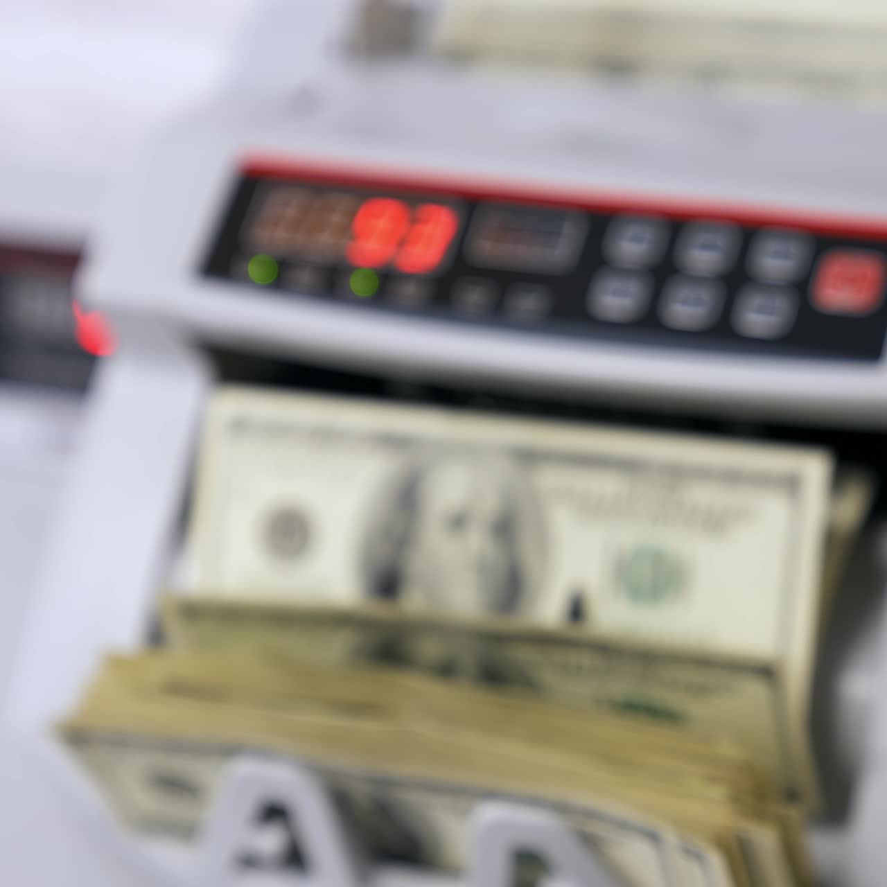 Conteggio delle banconote in dollari. Macchina contabanconote con banconote da 100 dollari. La mano di una donna tiene un pacchetto di valuta cartacea nazionale statunitense. Concetto di finanza. Primo piano. Sfondo sfocato.