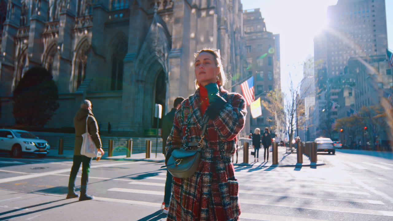 New York, USA, 25 ottobre 2025: Donna che attraversa la strada vicino alla Cattedrale di San Patrizio a New York. Scatto a figura intera di una donna in cappotto a quadri in piedi sulle strisce pedonali a Manhattan.