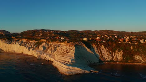 Aerial-shot-over-a-stunning-cliff-by-the-sea-on-the-island-of-Sicily,-Italy