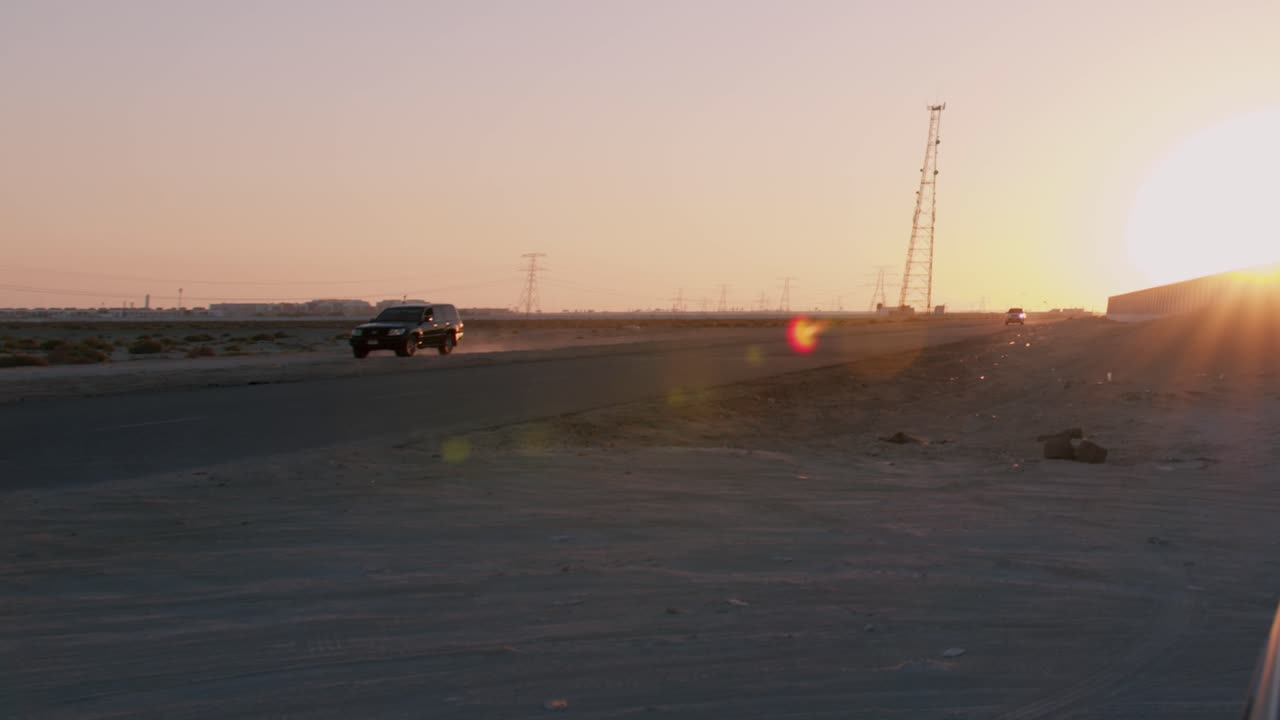 Black SUV passes the camera driving on a highway at dusk.