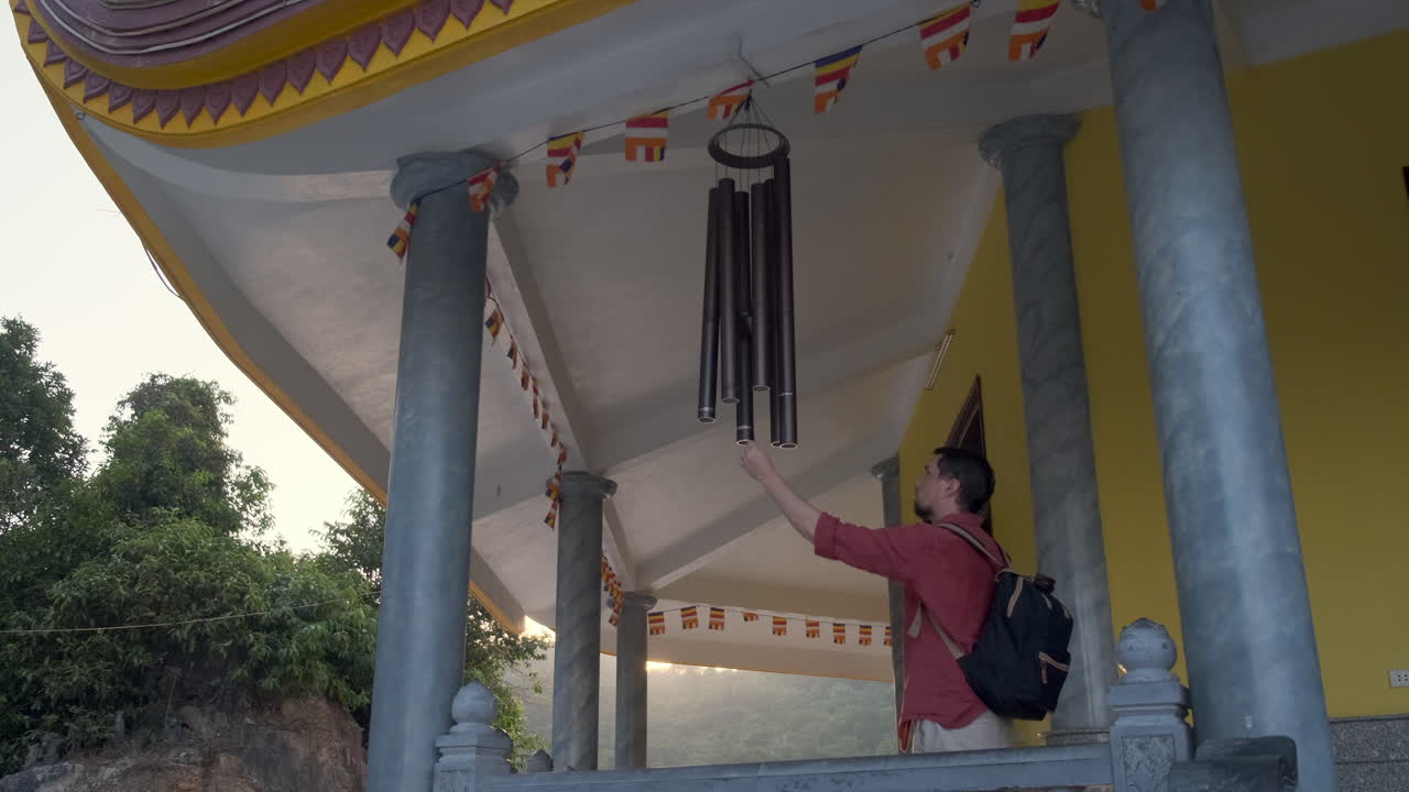 Man interacting with wind chime at a Buddhist temple
