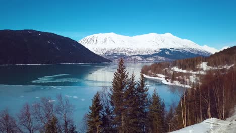 4k drone video of snow covered lakeside mountains in alaska during winter