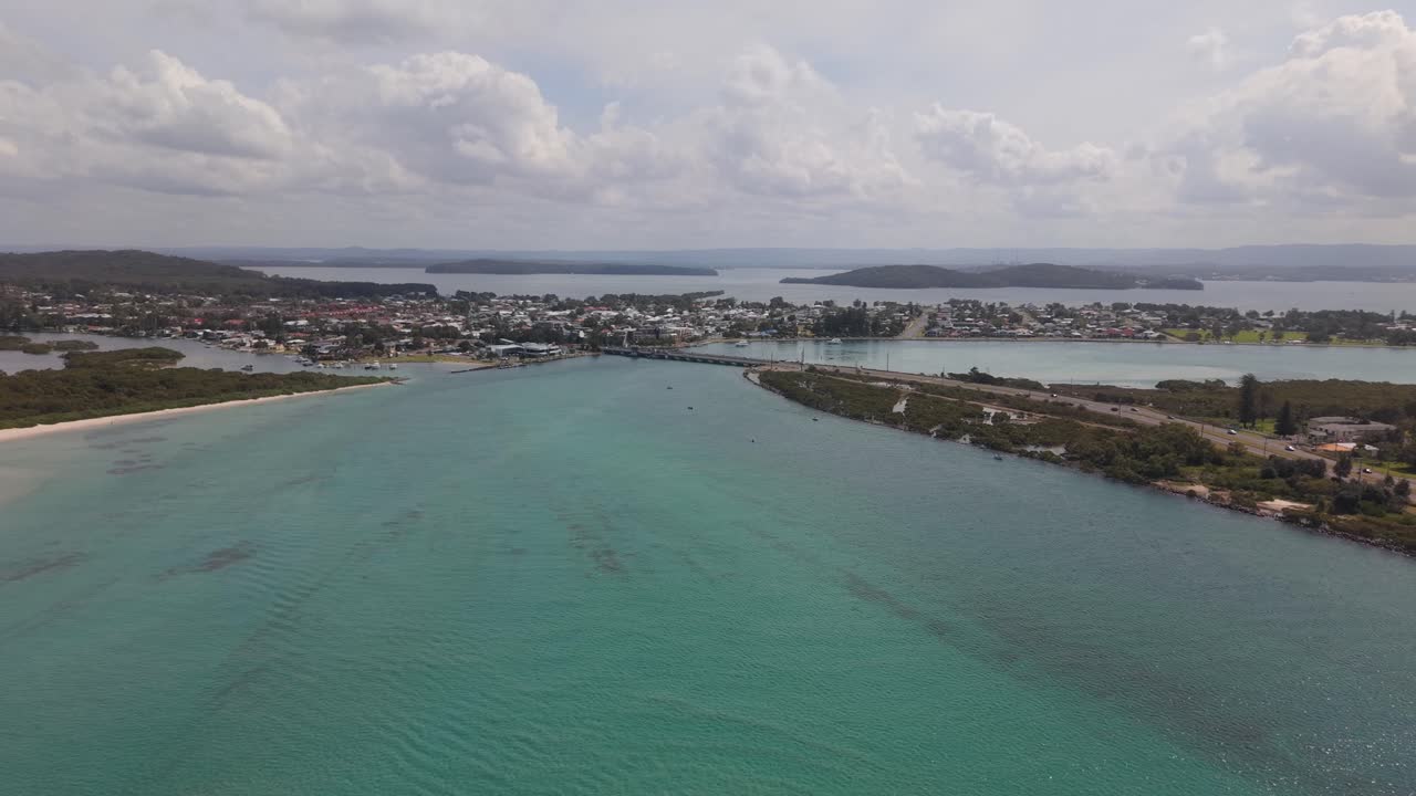 Aerial panoramic approach to Swansea Channel Bridge lifting for boats midday, turquoise water, light clouds