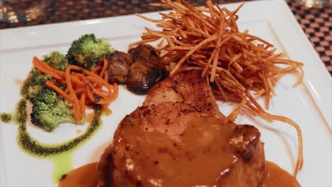 plato de filete de mignon con brócoli y papas fritas en un plato blanco