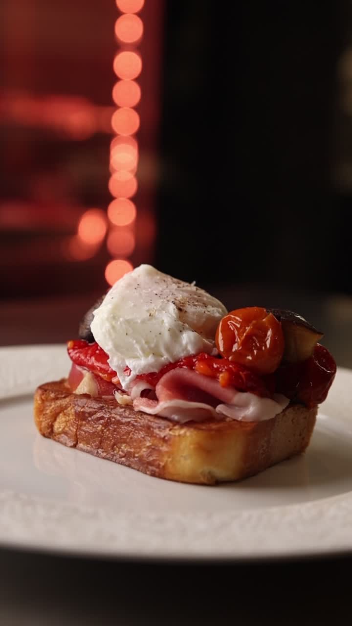 Toast gourmet con uovo in camicia, prosciutto e pomodori arrostiti.