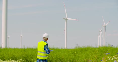 工程師使用數碼平板電腦在風車農場檢查風力輪