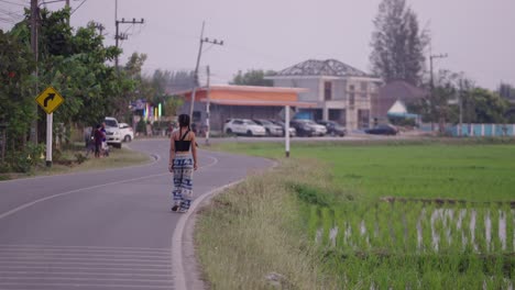 person walking on a rural road next to a rice field