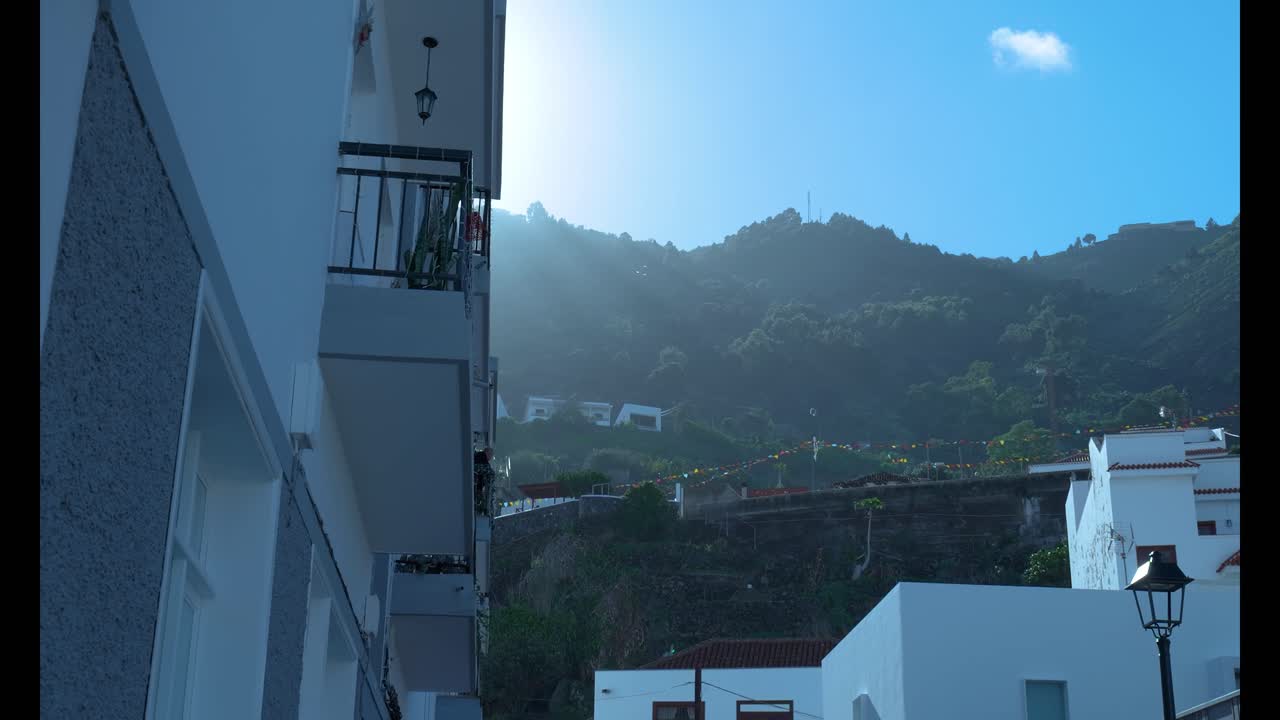 白い建物が建ち並ぶ山村を明るい太陽が照らす