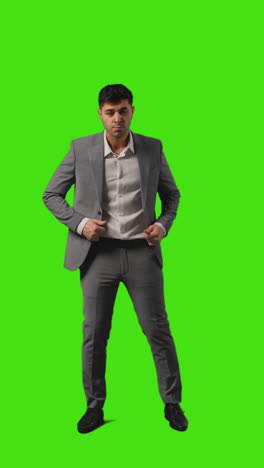 Vertical-Video-Full-Length-Shot-Of-Businessman-Walking-Into-Frame-Standing-Against-Green-Screen-Folding-Arms-Against-Green-Screen