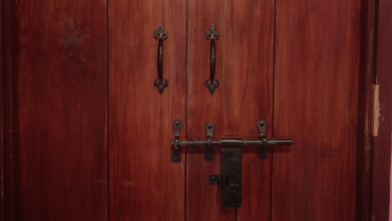 vista de cerca de una puerta de madera con manijas ornamentadas y un robusto mecanismo de cerradura de metal