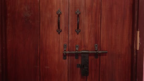 close-up view of a wooden door featuring ornate handles and a sturdy metal latch mechanism