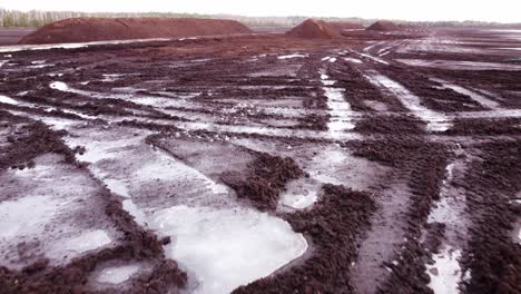 Frozen-tire-marks-on-peat-extraction-site,-aerial-drone-view