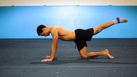 a still shot from a side view of a guy doing leg raises on all six as a lower back strength exercise