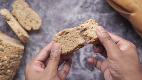 mano sosteniendo un pedazo de pan de trigo entero en rodajas