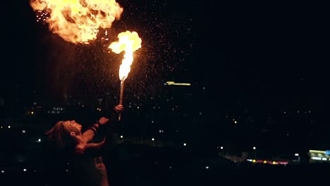 young blond male breathes out large stream of fire making fireball with kerosene spray slow motion shot