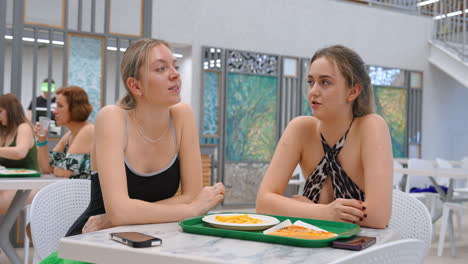 two women eating lunch in a poolside cafe
