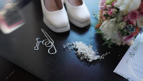 close up of bridal shoes bouquet jewelry and hair comb arranged on black table before wedding