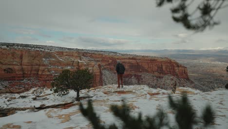 Hombre-Caminando-Al-Borde-De-Un-Cañón-Nevado-En-Una-Tormenta