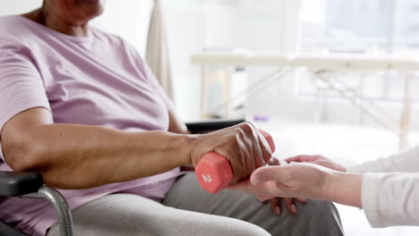 mujer anciana diversa haciendo ejercicio con peso y médico femenino aconsejando en el hospital, cámara lenta