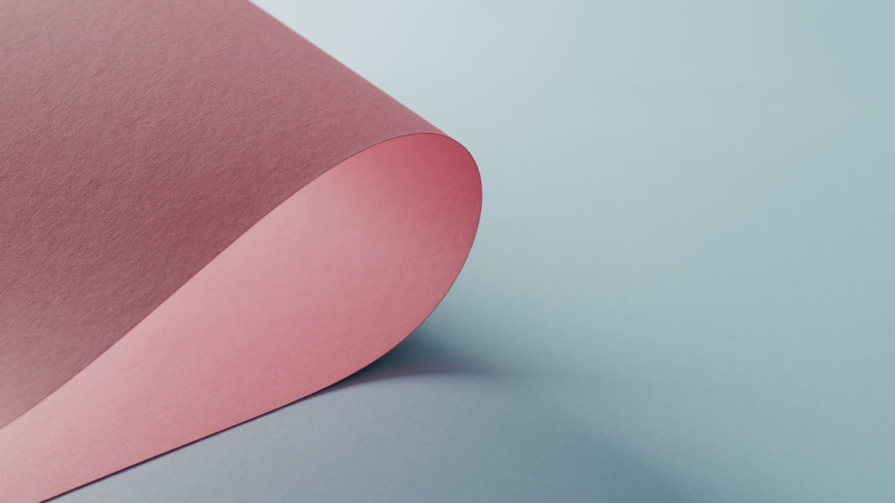 primer plano de un pedazo de papel enrollado de color rosa sobre un fondo azul pálido con espacio de copia en cámara lenta