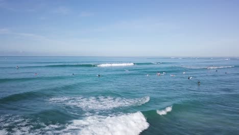 Multitud-De-Surfistas-En-El-Agua-Esperando-Una-Ola-En-La-Playa-De-Waikiki-Honolulu-Hawaii,-Empuje-De-Muñeca-Aérea