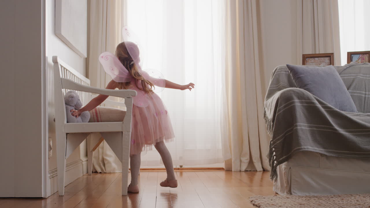 niña linda bailando juguetón fingiendo ser bailarina niño feliz divirtiéndose jugando a vestirse con traje de ballet con alas de hada en casa 4k
