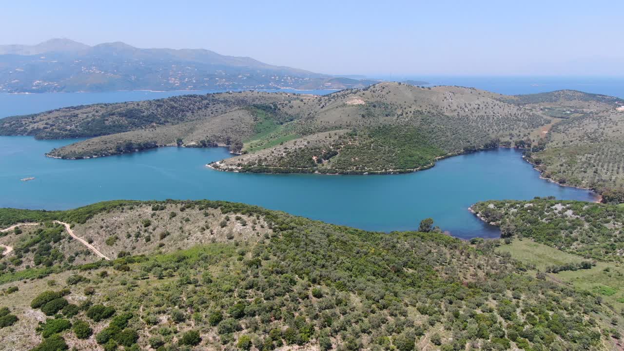vista de avión no tripulado en albania volando sobre el paisaje verde montañoso al lado del mar con montañas en la parte de atrás