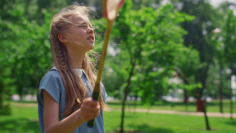 portrait of focused girl playing game on nature. badminton training on meadow.