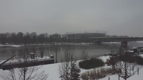 video de drones del estadio nacional de varsovia mientras el tren pasa por un puente en un día de nieve sobre el río vistula1
