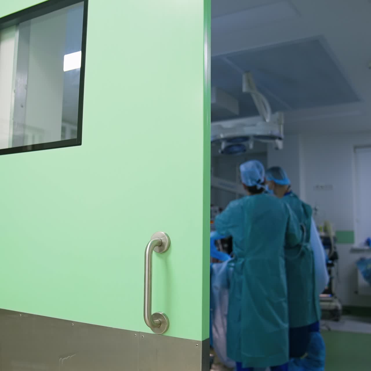 Operação ocorrendo em uma sala cirúrgica moderna. Grupo de médicos perto da mesa de operação. Filmagem na porta da sala de cirurgia.