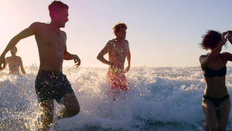 friends having fun in the ocean at sunset