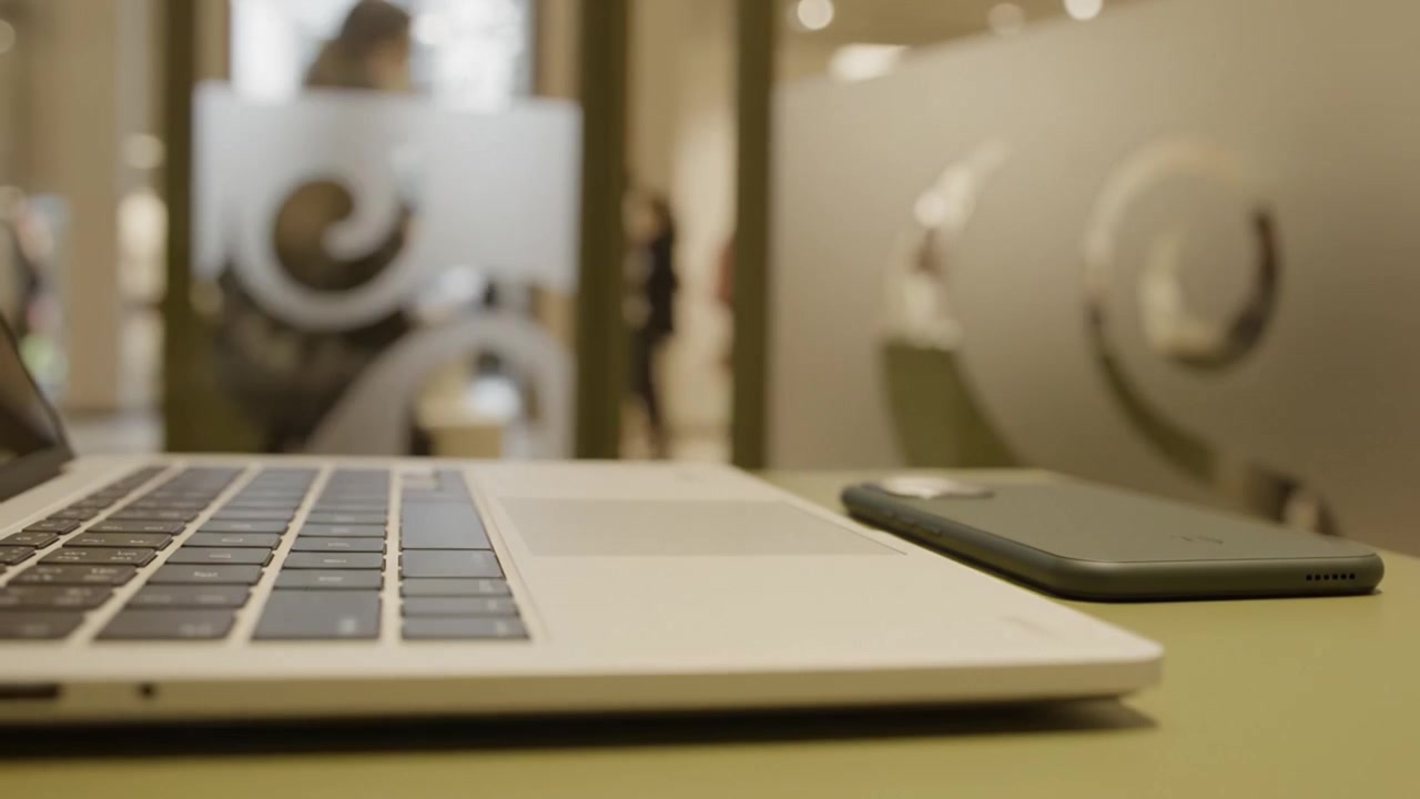 Una vista ravvicinata di un laptop e uno smartphone su una scrivania elegante, circondati da un design d'interni contemporaneo in un ambiente di lavoro moderno.