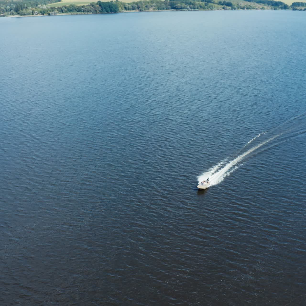 Panoramic view of a wide blue river among nature. Motor boat floating in the middle of the river in summer. Aerial view.