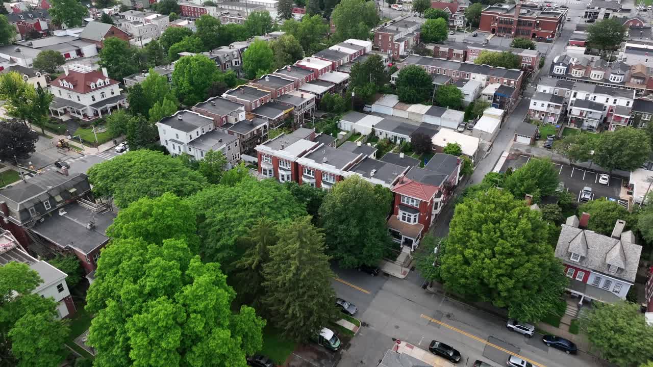Quiet residential neighborhood in Lancaster, Pennsylvania, USA. Tree-lined streets, historic brick houses, and peaceful small-town atmosphere captured on a clear summer day. Aerial flyover shot.