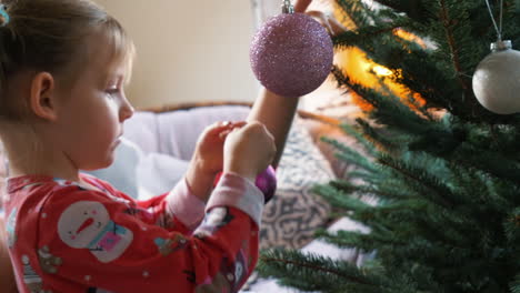 a child adds an ornament to a christmas tree to decorate for the holidays