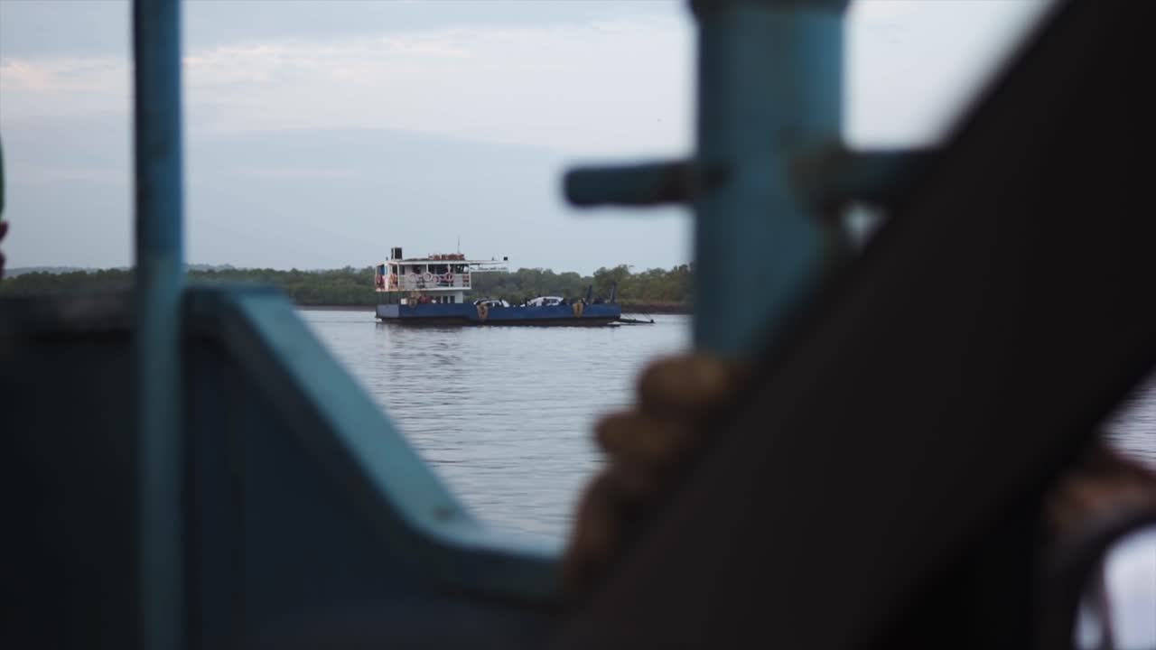 pov shot: un barco de carga en la costa se ve desde otro barco que se esconde detrás de la parrilla