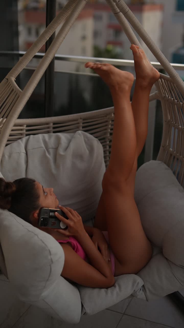 mujer relajándose en una silla colgante en el balcón