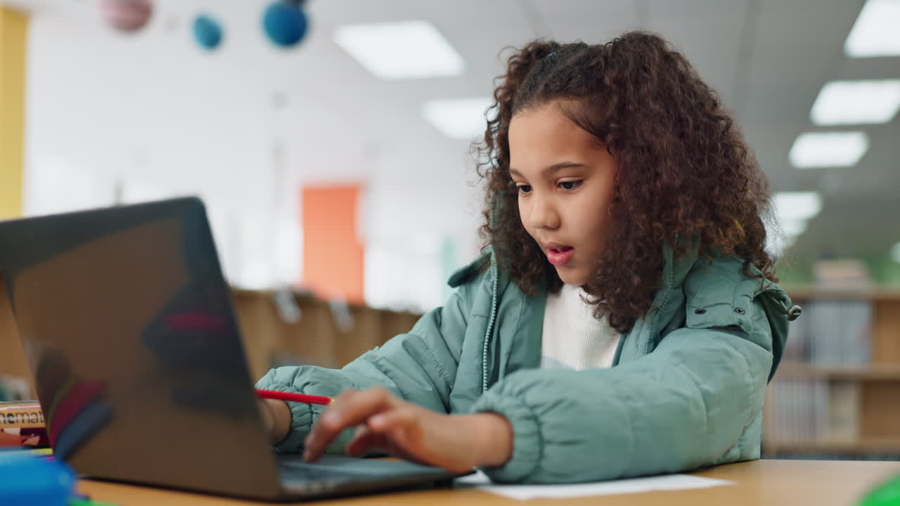 Girl studying with a laptop in a library