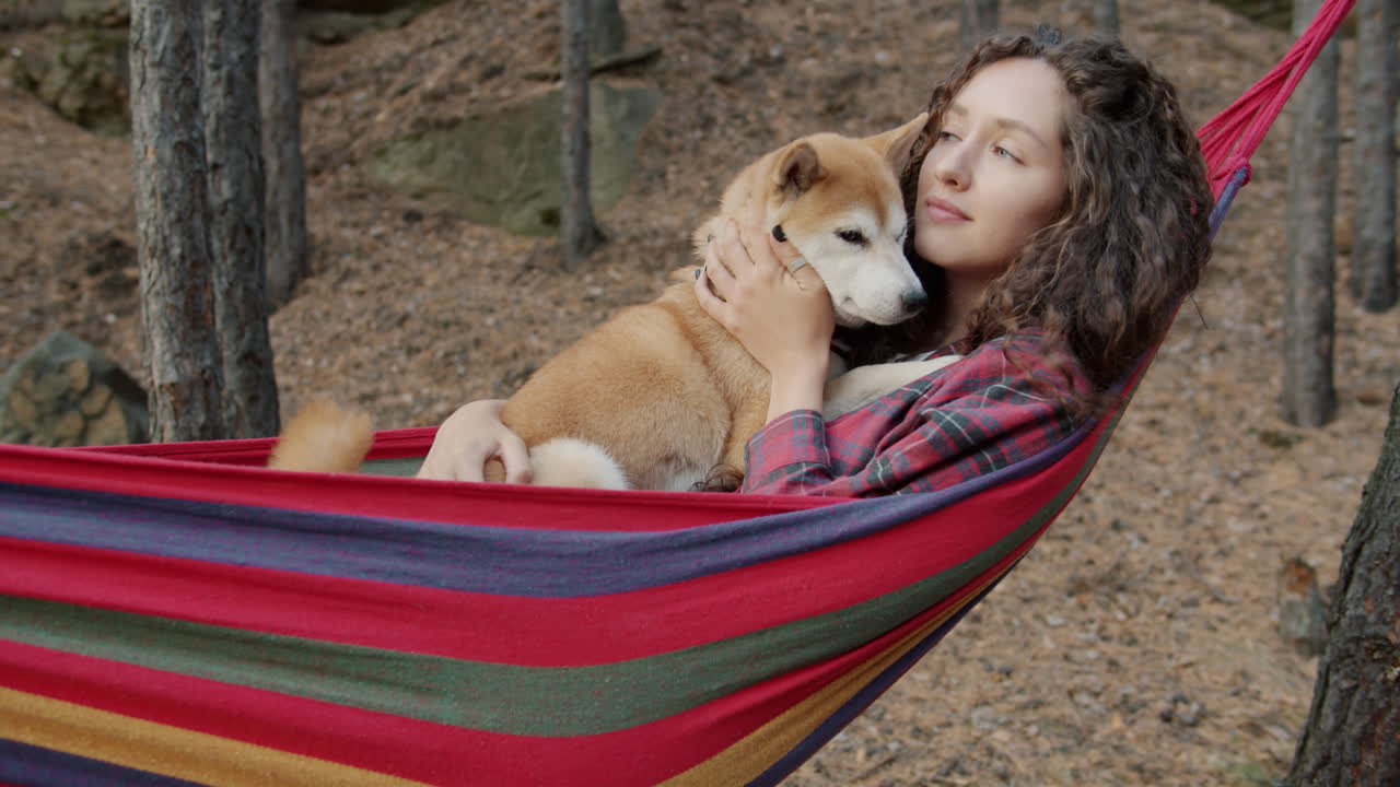 Woman relaxing in a hammock with her dog in a forest