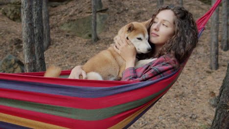 woman relaxing in a hammock with her dog in a forest