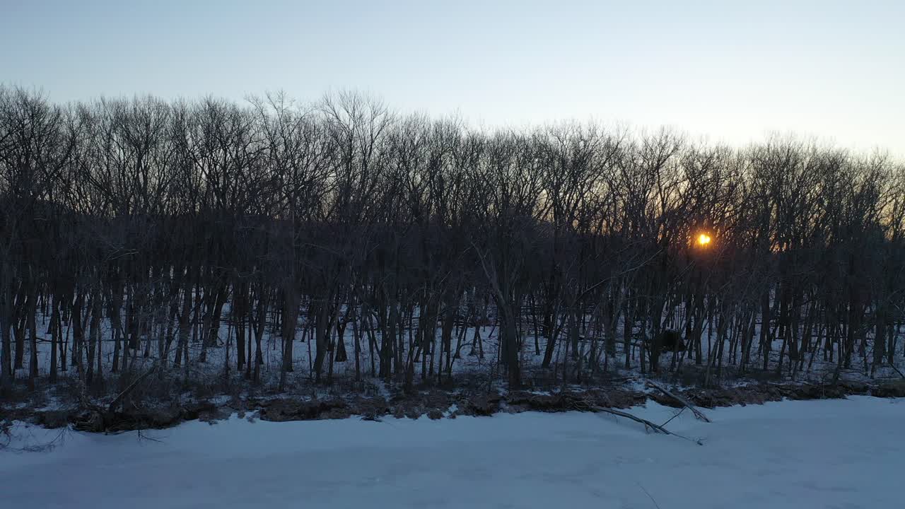 얼어붙은 강과 숲 위에서 겨울 해가 지는 모습