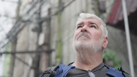 viejo hombre europeo de cabello gris al aire libre mirando a su alrededor con curiosidad