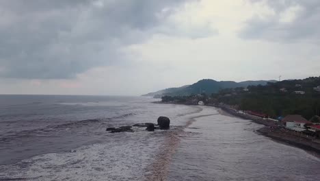 popular surf spot, el tunco beach in el salvador, during an overcast and cloudy day - aerial footage - dolly out