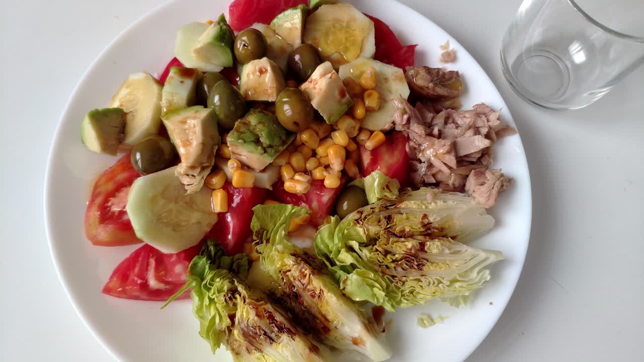 Mixed salad with tomatoes, cucumbers, avocado, olives, and grilled lettuce, paired with gazpacho