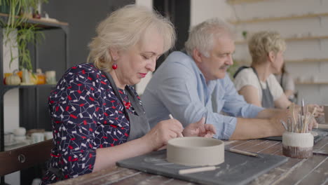 Three-elderly-people-work-on-a-potter's-wheel-in-slow-motion