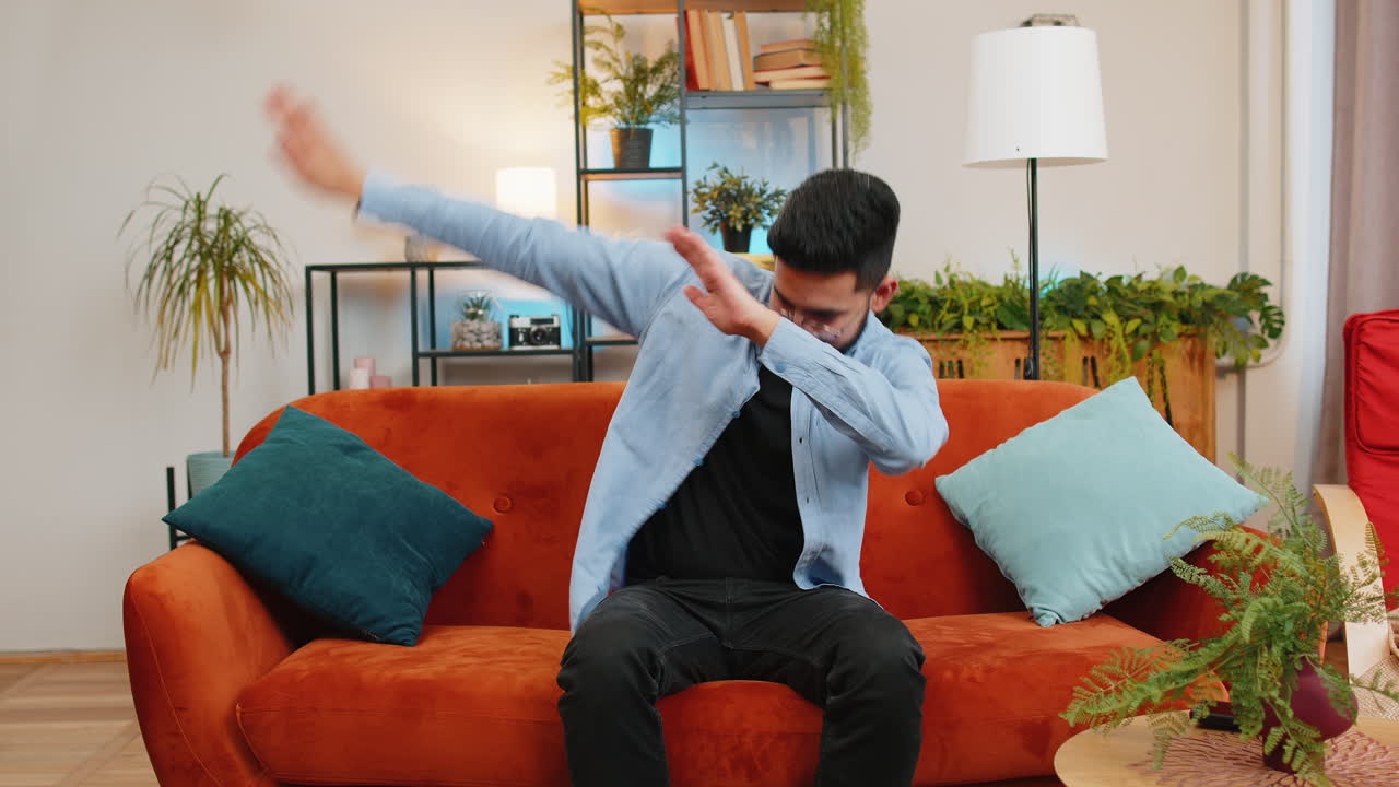 hombre indio alegre y emocionado divirtiéndose bailando levantando las manos haciendo bailar al ganador del dub en casa