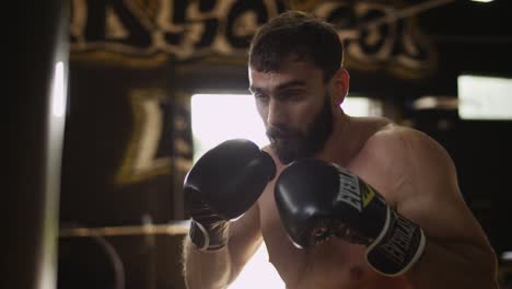 Boxer-Schlägt-In-Boxhandschuhen-Auf-Den-Boxsack-Im-Fitnessstudio.-Sportler-Arbeitet-Hart